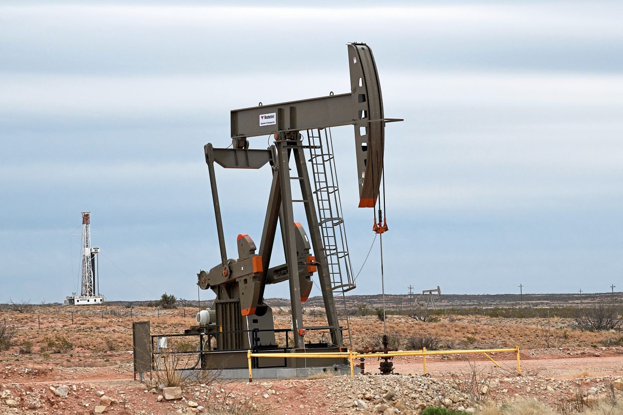 FILE PHOTO: A pump jack operates in front of a drilling rig owned by Exxon near Carlsbad, New Mexico, U.S. February 11, 2019. Picture taken February 11, 2019. To match Insight USA-SHALE/MAJORS . REUTERS/Nick Oxford/File Photo