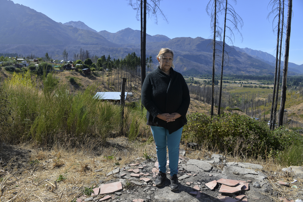 Alejandra Alaniz está de pie en el piso que fue de su casa, lo único que quedó tras el incendio de 2021 en la zona de Parcela 26. Foto: Chino Leiva