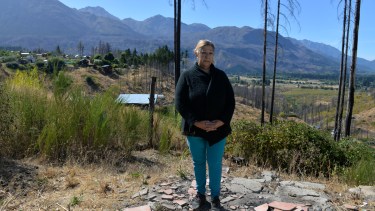 Alejandra Alaniz está de pie en el piso que fue de su casa, lo único que quedó tras el incendio de 2021 en la zona de Parcela 26. Foto: Chino Leiva