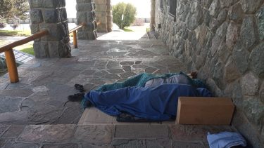 Dos personas duermen afuera de la Biblioteca Sarmiento en el Centro Cívico.