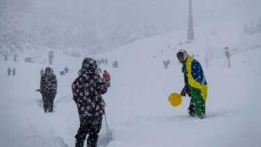 Un turista posa con la bandera de Brasil en la nieve en Bariloche. Foto: Marcelo Martínez 