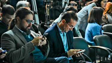 Martín Regueriro y Jorge Tobares consultan sus mensajes antes de firmar un convenio con el gobernador Rolando Figueroa (Matías Subat)