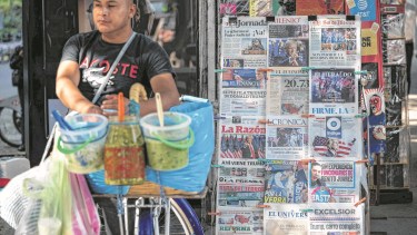  Un hombre vende tacos en un puesto con diarios que informan la victoria de Trump (Photo by Yuri CORTEZ / AFP)