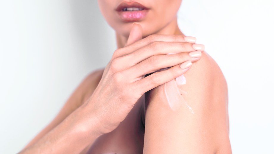 Close beauty portrait of topless woman with perfect skin holding bottle of shampoo, lotion, apply on shoulders and body, on white background