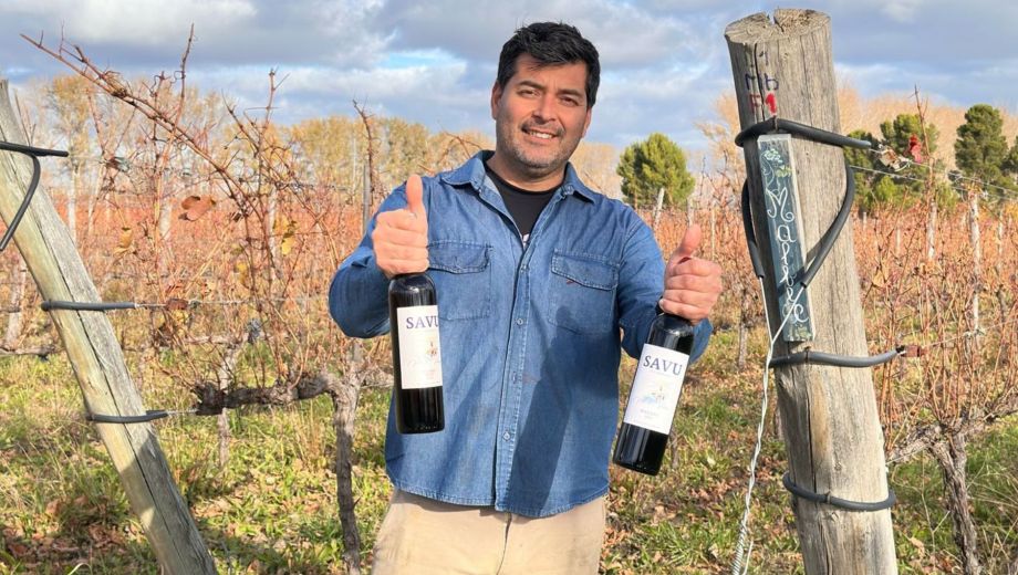 Juan Alberto Millaman posando entre los viñedos con dos botellas de la producción artesanal de la bodega. Foto: gentileza.