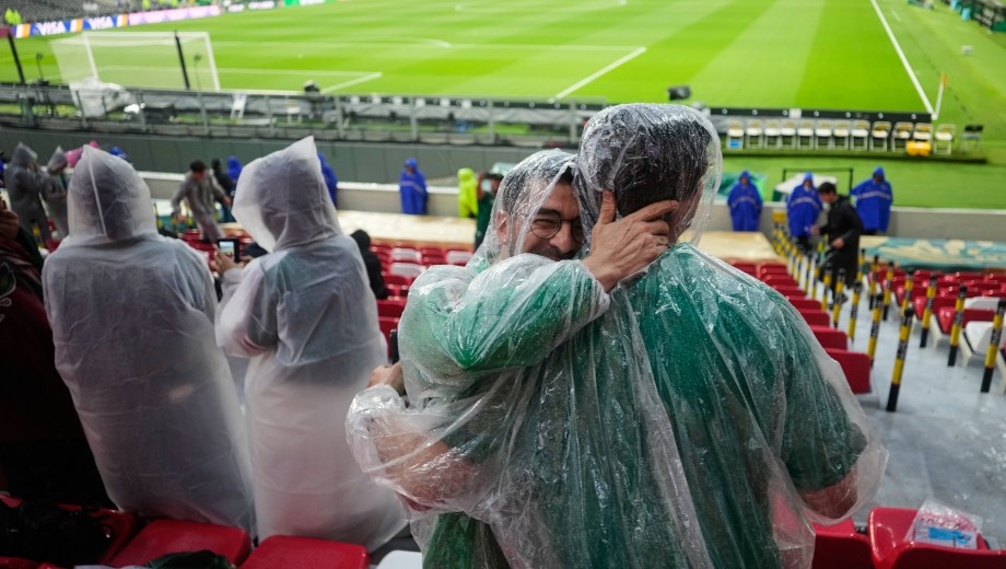 Los hinchas esperan el inicio del partido en el Estadio Azteca bajo la lluvia y con pilotos. (Foto: AP)