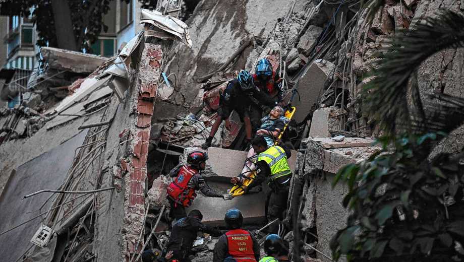 Rescue workers carry a person on a stretcher out of a collapsed building following an earthquake in Caracas on June 24, 2026. A magnitude 7.1 earthquake struck Venezuela on Wednesday, the United States Geological Survey (USGS) reported, triggering panic in Caracas, according to AFP journalists. The tremor, which was followed by several aftershocks, was also felt in Colombia. (Photo by Juan BARRETO / AFP)
