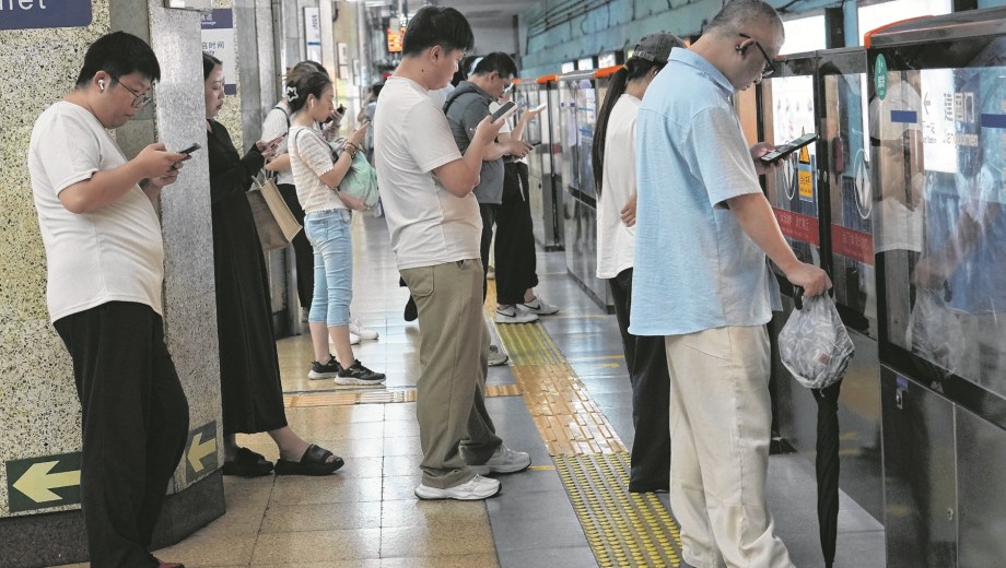 People looking their mobile phones while waiting for the train in Beijing, China Wednesday, July 22, 2026. (AP Photo/Achmad Ibrahim)