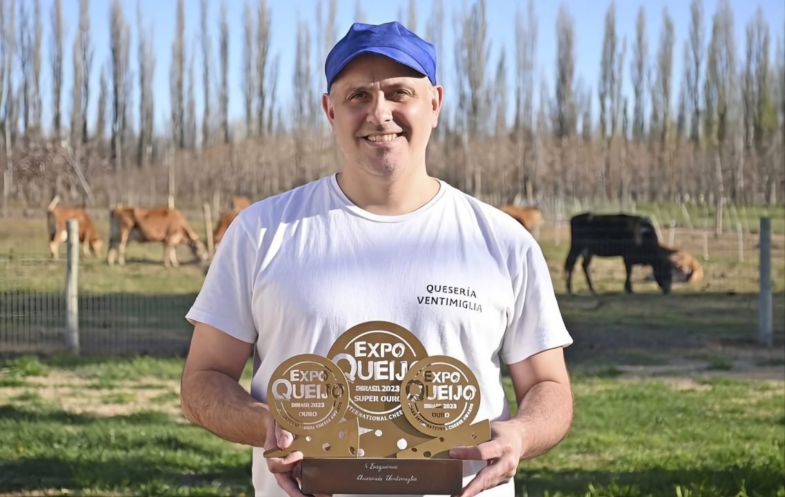 De fondo, las vacas lecheras. En primer plano, Mauricio posando con premios obtenidos en Brasil.