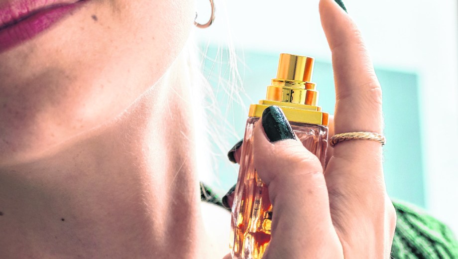 Caucasian woman applying perfume to her neck